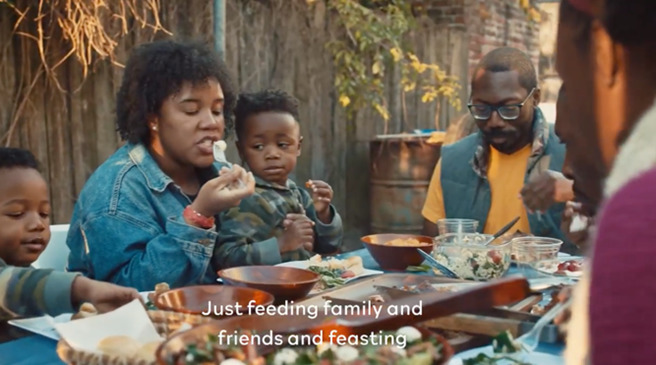 Image of five members of a family eating bbq food together.